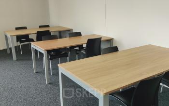 Office space rental at Dr. Nolenslaan 157, Sittard with several desks and chairs in a bright room with carpet flooring.