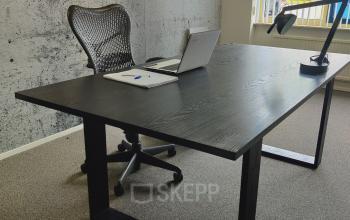 Modern office with a sleek black desk, ergonomic chair, laptop, and desk lamp at Dr. Nolenslaan 157, Sittard. Perfect for office space rental.