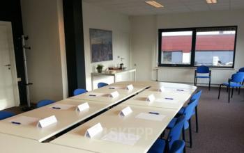 Bright office space at Nusterweg 63, Sittard, featuring a conference table with blue chairs, ideal for rent office space and meetings.