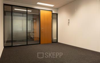 Empty office space with glass walls and carpeted floor, located at Curieweg 9, Spijkenisse, available for office space rental.