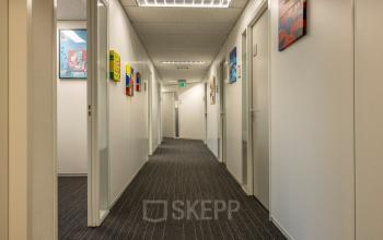 Hallway of an office for rent at Curieweg 9, Spijkenisse, showcasing framed artwork on walls and a modern ceiling. Ideal for those seeking office space rental.