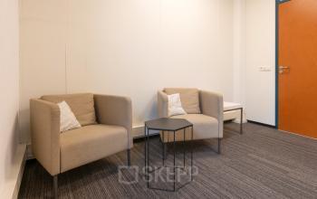 Modest office space at Curieweg 9, Spijkenisse, featuring two comfortable chairs and a small table, suitable for meetings or relaxation. Ideal for office space rental.