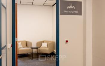 Cozy office space to rent at Curieweg 9, Spijkenisse, featuring a small waiting area with two beige armchairs and a round black table.