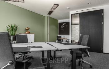 Modernes Büro in der Königstraße 38, Stuttgart Mitte, mit mehreren Schreibtischen auf grauem Teppichboden und grüner Wandfarbe.