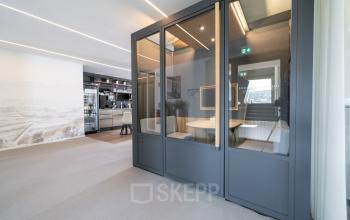 Moderner Büroraum mit Besprechungskabine und Regalen in Stuttgart Mitte. Ideale Bürofläche mieten für kreative Meetings.