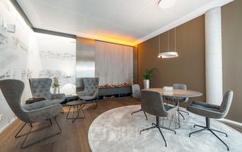 Moderner Besprechungsraum in Stuttgart Mitte mit stilvollen Sesseln und Tisch, ideal für büroraum mieten. Dezente Beleuchtung und Wanddekoration schaffen eine einladende Atmosphäre.