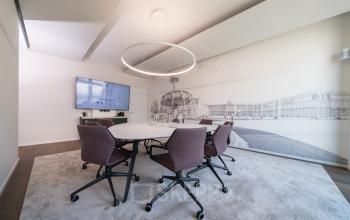 Moderner Konferenzraum in der Königstraße 35, Stuttgart Mitte, geeignet zum Büroraum mieten, mit rundem Tisch, Stühlen und Wandbild des Schlossplatzes.