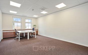 Bright office space for rent at Bredaseweg 8, Breda Terheijden, featuring clean lines and a minimalist design with desks and chairs under ample lighting.