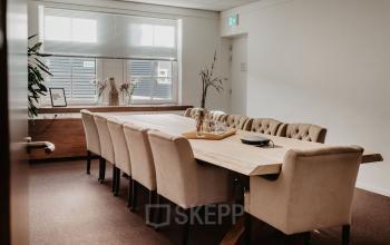 Spacious conference room in Breda Terheijden, featuring a long table with plush chairs and natural light streaming through the windows, ideal for office space rental.