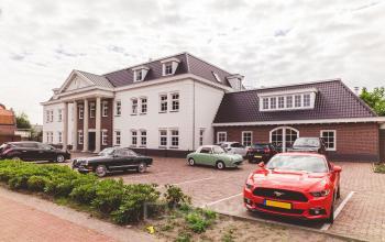 Exterior view of a classic two-story office building located at Bredaseweg 8, Breda Terheijden, with parked cars in the lot. Ideal for those seeking office space rental with easy parking access.