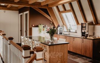 Cozy pantry area in an office space for rent at Bredaseweg 8, Breda Terheijden, featuring wooden beams, a coffee machine, and bar seating under skylight windows.