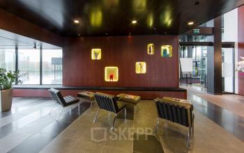 Elegant office space rental at Hart van Brabantlaan 12-16 in Tilburg featuring a stylish waiting area with modern seating and artistic wall decor.