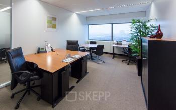 Well-lit office space rental at Hart van Brabantlaan 12-16, Tilburg, with modern desks, chairs, and a large window offering ample natural light.