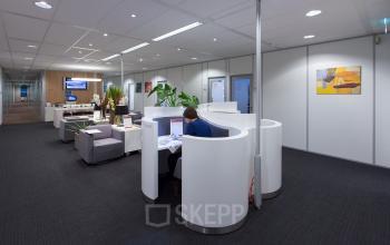Modern and neat office space rental at Hart van Brabantlaan 12-16, Tilburg, with a person working at a curved reception desk.