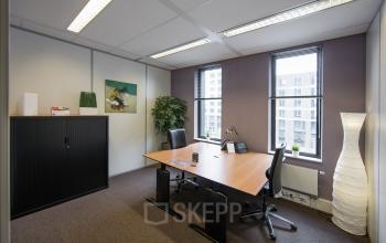 Well-lit office space rental at Hart van Brabantlaan 12-16, Tilburg, with a large desk, chairs, and tasteful decorations.