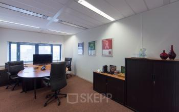 Modern office space rental at Hart van Brabantlaan 12-16, Tilburg with a sleek desk setup and a view of the city.