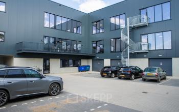 Exterior view of the office building at Kapitein Rondairestraat 8, Tilburg, featuring a parking area and a modern design, highlighting available office space rental options.