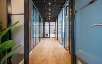 Bright office hallway with glass doors and wooden floors at Kapitein Rondairestraat 8, Tilburg, perfect for office space rental.