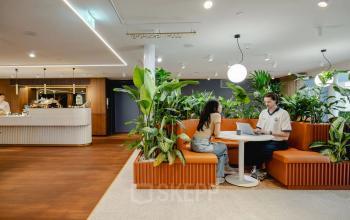 Modern office space at Moreelsepark 1, Utrecht Central Station with two people collaborating at a round table surrounded by plants, ideal for office space rental.