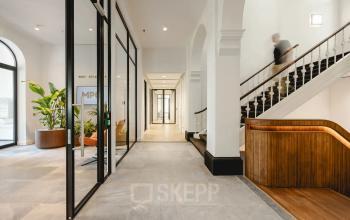 Spacious office entrance with modern design, featuring glass partitions and elegant wooden accents, located at Moreelsepark 1. Ideal office space rental opportunity in Utrecht Central Station.