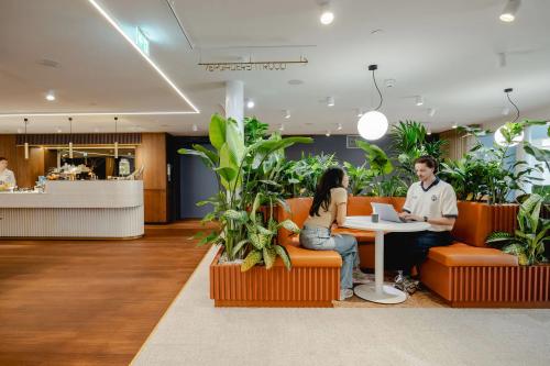 Modern office space at Moreelsepark 1, Utrecht Central Station with two people collaborating at a round table surrounded by plants, ideal for office space rental.