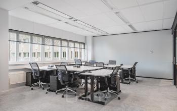 Modern furnished office space with multiple desks and chairs, located at Leidseveer 2-10, Utrecht Central Station, ideal for rent office space. Natural light fills the room through large windows.