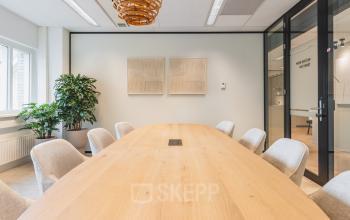 Modern conference room with a large wooden table and comfortable chairs, ideal for office space rental at Utrecht Central Station.