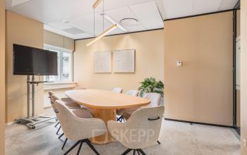 Bright office space rental at Utrecht Central Station featuring a modern conference room with a wooden table, comfortable chairs, and a large screen.