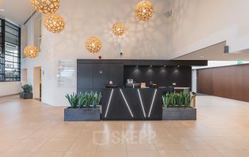 Modern office to rent at Utrecht Central Station with stylish lighting and reception desk, ideal for office space rental.