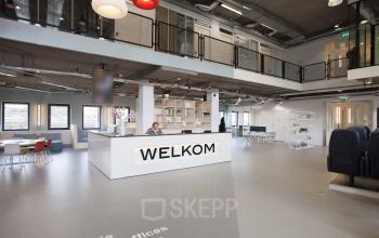 Spacious reception area at Arthur van Schendelstraat 650, Utrecht Central Station with a modern design and reception desk. Office space rental available, featuring seating areas and ample natural light.
