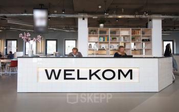 Modern reception area at Arthur van Schendelstraat 650, Utrecht Central Station, with large 'WELKOM' sign and people working on laptops.