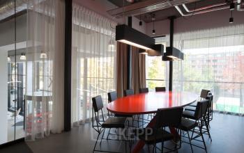 Modern conference room with a large red oval table and stylish chairs at Arthur van Schendelstraat 650, Utrecht Central Station.
