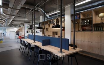 Modern office space rental in Utrecht Central Station, located at Arthur van Schendelstraat 650, featuring an open floorplan with communal workspaces, lockers, and contemporary furnishings.