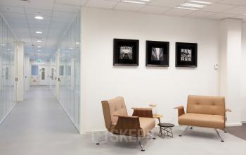 Modern office interior at Arthur van Schendelstraat 650, Utrecht Central Station, featuring stylish seating and framed photos on the wall, available for office space rental.