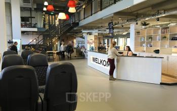 Modern reception area at Arthur van Schendelstraat 650, Utrecht Central Station, featuring people engaged in business activities near a welcoming desk.