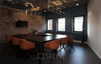 Modern conference room in an office located at Arthur van Schendelstraat 650, Utrecht Central Station with brick wall, large table, and brown chairs.