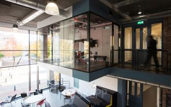 Office to rent at Arthur van Schendelstraat 650 in Utrecht Central Station; modern interior with glass-enclosed meeting room, open workspace, and vibrant seating areas.
