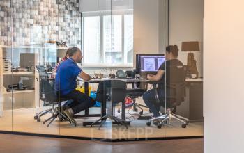Office to rent at Leidseveer 2-10, Utrecht Central Station, with two people working at desks in a glass-walled room with modern furnishings.