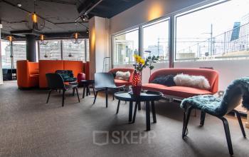 Modern lounge area with several sofas, chairs, and tables, located in office space rental at Leidseveer 2-10, Utrecht Central Station.