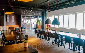 Bright, modern workspace at Leidseveer 2-10 in Utrecht Central Station with large windows, contemporary furnishings, and long tables. Ideal for office space rental.