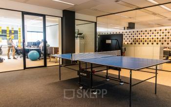 Modern office space at Leidseveer 2-10, Utrecht Central Station, featuring a ping pong table and glass-enclosed workspaces. Ideal for office space rental.