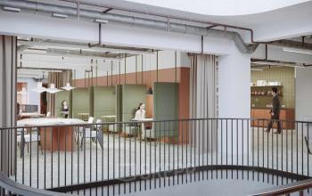 Modern Utrecht office space rental at Lange Viestraat 2 A featuring sleek design and employees engaged in discussion.