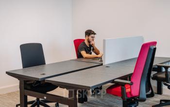 Modern workspace with chairs and desks, a professional is working on a laptop at Kromme Nieuwegracht 3, Utrecht Center, office space rental available.