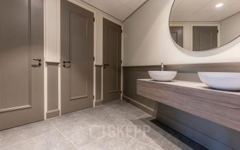 Modern restroom at Kromme Nieuwegracht 3 in Utrecht with sleek fixtures and a large circular mirror.