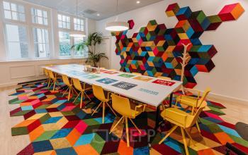 Vibrant office space rental at Kromme Nieuwegracht 3 in Utrecht Center with colorful decor, long table, and bright chairs.