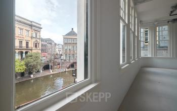 Bright interior view at Oudegracht 161, Utrecht Center, showcasing large windows overlooking the canal, a potential space for office to rent.