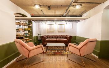 Office space rental in Utrecht Center, Nicolaas Beetsstraat 216, featuring a cozy lounge area with a leather sofa, two armchairs, and a coffee table on a colorful rug.
