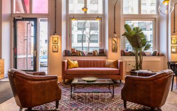Inviting lounge area at Nicolaas Beetsstraat 216 in Utrecht Center featuring leather chairs, a sofa, and bookshelves, ideal for informal meetings and relaxation.