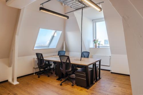 Bright office space rental in Utrecht Center at Nicolaas Beetsstraat 216, featuring wooden floors, large windows, and modern desks and chairs.