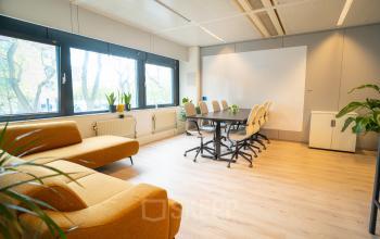 Bright office space with a long conference table, chairs, and yellow couches at Bernadottelaan 13 in Utrecht Kanaleneiland.